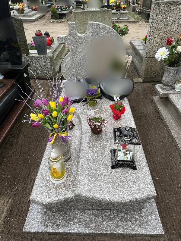 Grób z jasnego granitu z bukietem tulipanów i wielkanocnym zniczem