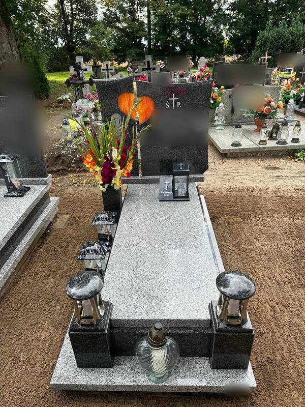 Ciemny granitowy nagrobek z bukietem mieczyków i zniczami
